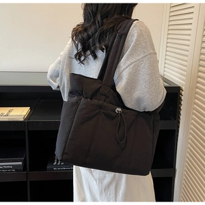 Quilted black tote bag detail showing the large front pocket and drawstring closure design