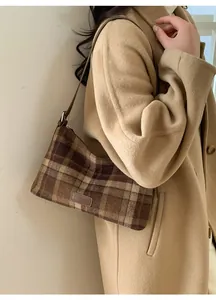Brown plaid hobo bag with leather strap and fashion tag shown on a camel wool coat