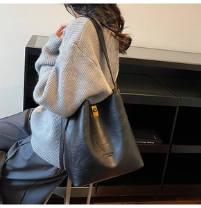 Close-up of black leather bucket bag featuring a gold twist lock and brand logo