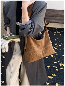 Detailed side view of a brown suede tote bag with decorative stitching on the shoulder strap