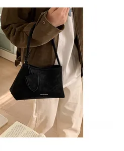 Detail view of black suede shoulder bag with a matching small round pouch accessory