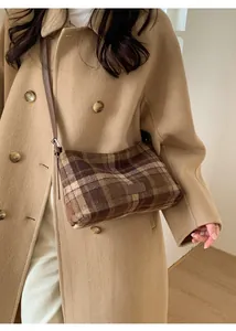 Detail view of brown vintage plaid crossbody bag with a leather strap on wool coat