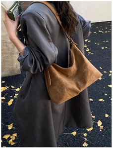 Brown suede hobo tote bag shown in a street style view over a ginkgo leaf background