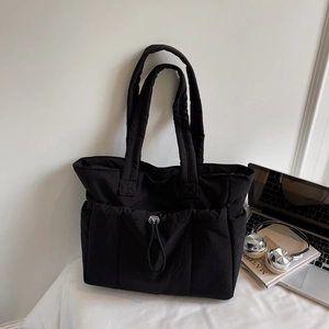 Detail of black quilted tote bag with drawstring pockets and lightweight nylon texture