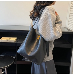 Detail view of large black faux suede tote bag with golden twist lock and printed logo
