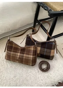 Detailed view of vintage plaid wool shoulder bags with leather straps on a cozy carpet