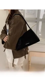 Detail of black suede shoulder bag featuring minimalist Fashion & Bags text on model