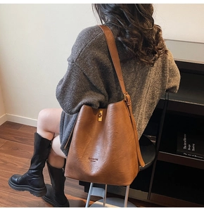 Detail of dark brown faux leather bucket bag with Fashion bag NEW YORK text and strap