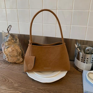 Detail of a brown suede hobo bag with mini pouch on a decorative plate