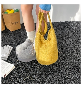 Détail d'un sac cabas jaune texturé et de sabots en feutre gris dans un décor chic et décontracté