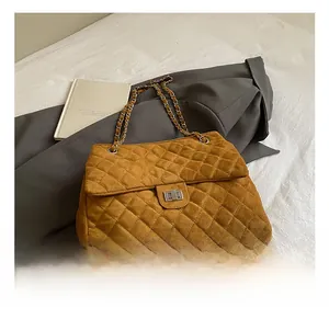 Détail du sac en daim matelassé ambre avec fermoir rotatif argenté et bandoulière chaîne