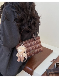 Détail d'un sac à main à carreaux avec breloque ours en peluche et poignée en cuir
