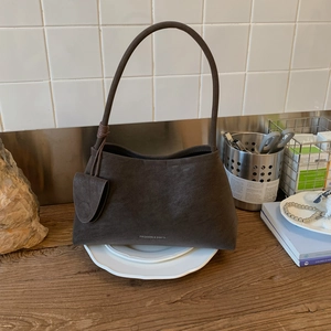 Close-up of retro brown suede half-moon shoulder bag with minimalist branding logo