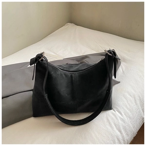 Detail shot of the black suede tote bag featuring cross-stitched seams and wide shoulder strap