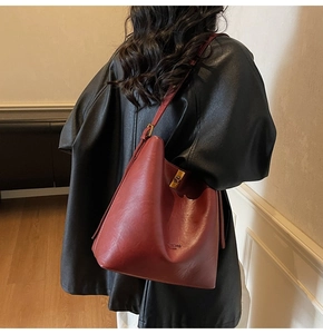 Detailed close-up of a burgundy suede tote bag featuring a gold buckle and embossed text