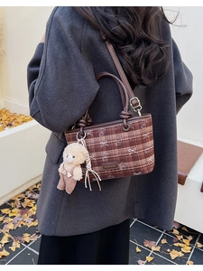 Détail du sac à carreaux avec pendentif ours et breloque peluche sur rue d'automne
