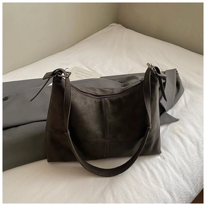 Detail view of dark brown suede tote bag featuring cross stitching and zipper closure