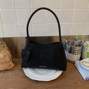 Detail of black suede hobo bag with white Fashion & Bags text and mini pouch accessory
