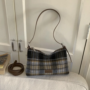 Detailed close-up of retro plaid fabric texture and fashion leather patch on tote bag