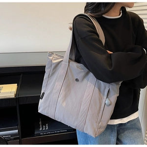 Detail of grey large capacity tote bag featuring reinforced handles and side zipper pocket