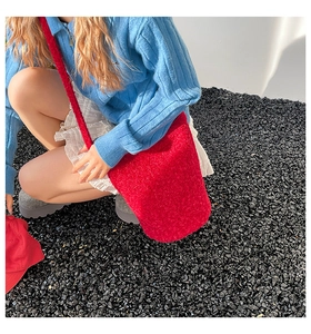 Détail du sac bandoulière en peluche rouge avec fleur 3D dans un décor de style urbain