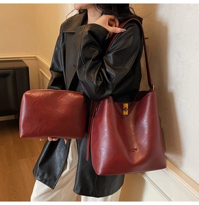 Detail of burgundy PU leather bucket bag with gold clasp and matching zipper pouch