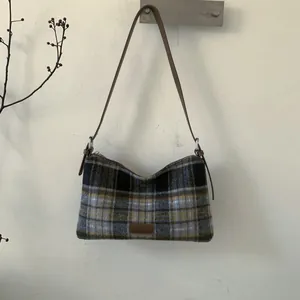 Detail of classic plaid pattern fabric and adjustable leather strap on a tote bag
