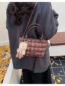 Vue détaillée du sac à bandoulière à carreaux marron avec un charmant ours en peluche