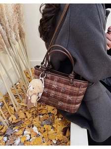 Détail du sac à carreaux avec imprimé ours et breloque peluche sur un manteau gris