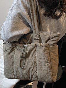 Padded olive green quilted tote bag with drawstring side detail for minimalist winter travel
