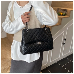 Sac fourre-tout matelassé noir avec chaîne argentée et fermoir pivotant porté par un mannequin