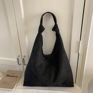 Detail of minimalist black suede tote bag with a unique knot handle design and soft texture