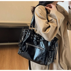 Detail van zwarte glanzende geoliede leren shopper met trekkoord en zilveren ritsvak