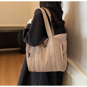 Detail of canvas tote bag showing side hidden zipper pocket and reinforced wide strap handles