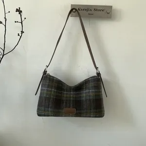 Detail of checkered plaid shoulder bag with vintage tweed texture and adjustable leather strap