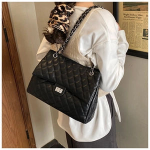 Détail de la texture matelassée classique et bandoulière chaîne argentée sur sac noir