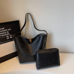 Detail view of the black leather bucket tote bag and matching zippered clutch set with gold hardware