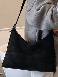 Minimalist black suede hobo tote bag with cross-stitch design on model for casual styling
