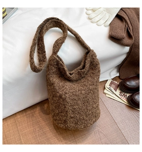 Détail du sac cabas en laine tricotée marron foncé avec texture bouclée sur lit blanc