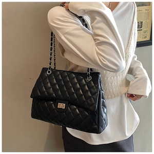 Détail du motif matelassé et du fermoir rotatif argenté sur le sac fourre-tout noir