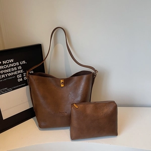 Detail view of brown suede bucket tote with golden lock and small zipper pouch