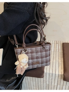 Vue détaillée du sac à carreaux vintage avec pendentif ours en peluche et sangle