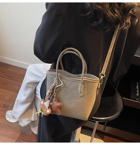 Detail der graugrünen matten Shopper-Tasche mit Bärenanhänger und verstellbarem Riemen
