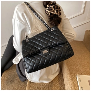 Détail du sac bandoulière matelassé noir avec chaîne argentée et fermoir rotatif en métal