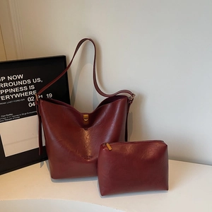 Detail view of burgundy faux leather bucket bag with matching small zipper pouch