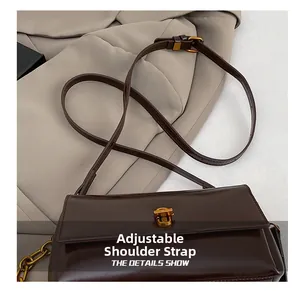Détail de la bandoulière réglable en cuir sur un sac à main carré marron foncé