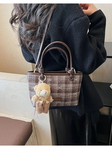 Vue détaillée d'un sac à bandoulière à carreaux marron avec broderie ours et breloque