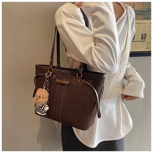 Détail du grand sac cabas en cuir marron foncé avec un charmant pendentif d'ours en peluche