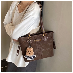 Vue latérale d'un sac cabas marron foncé vintage sur modèle avec charme d'ours