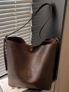 Retro dark brown suede-textured bucket tote bag with gold hardware and shoulder strap